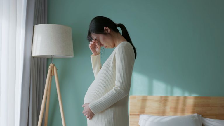 pregnant woman feel depression standing in bedroom