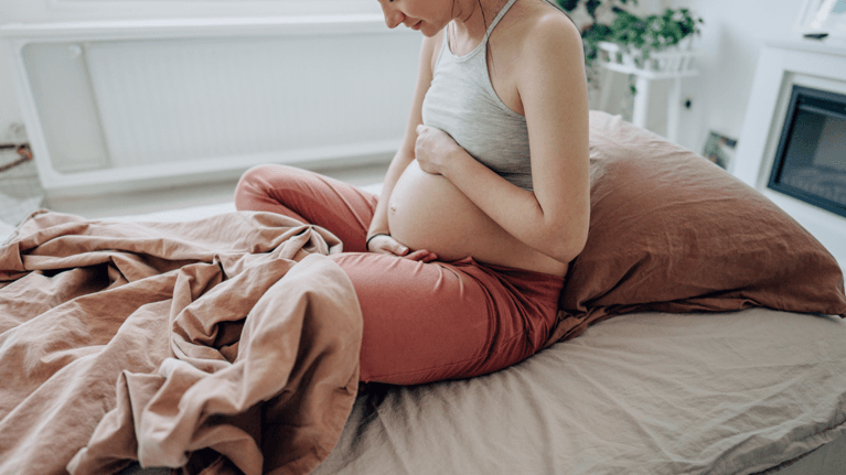pregnant woman looking down at her stomach